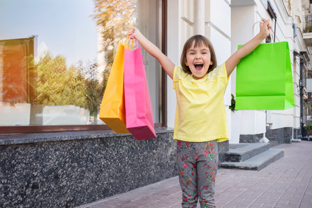 Little happy girl is holding colorful shopping bags.の写真素材