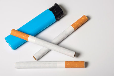 Cigarettes and a lighter, a close cigarette burn, the only one isolated at the white background.の写真素材