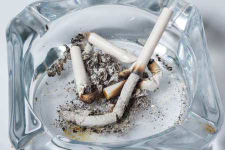A close-up of cigarette burns in a glass ashtray.