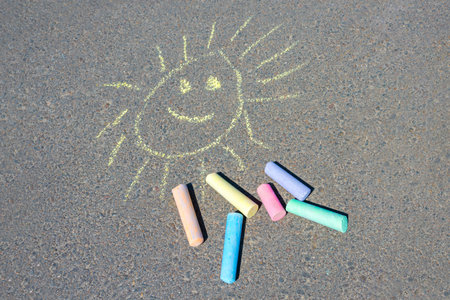 Colorful drawing of the sun, on the asphalt road. Multi-colored crayons set on asphalt close-up.の写真素材