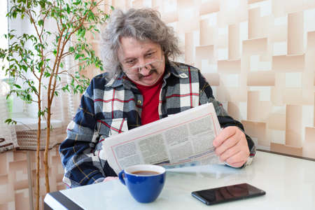 A portrait of an elderly man reading a newspaper.
