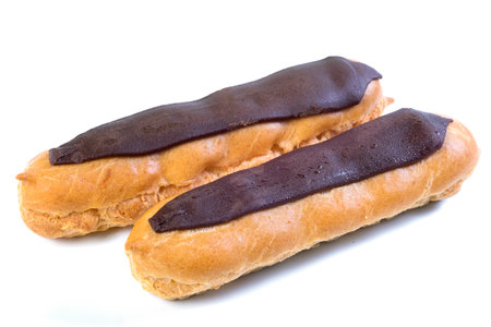 Two eclairs with dark chocolate with custard inside on a white background