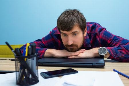 Portrait of a tired young man resting from work, lying at his desk. Lifestyle, Business and...