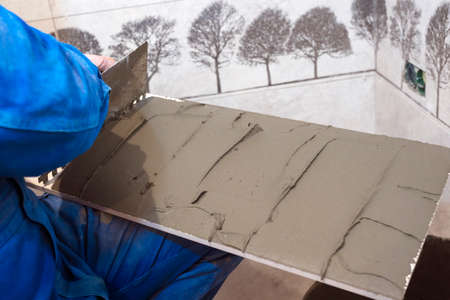 The builder is laying floor tiles. Tile adhesive