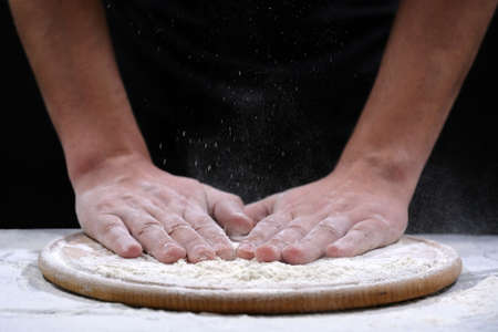 Chefs hands and flour on a dark background, close-up. Hands in flour.