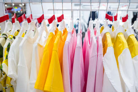 Variety of clothes hanging on rack in boutique. Bright clothes on hangers in a store close-up.の写真素材