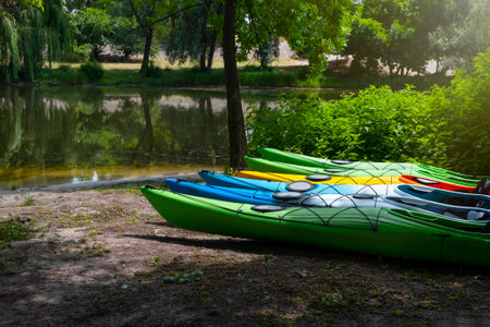 Boat parking on the river bank on a sunny summer day. Rental kayaks, boats in the park.の写真素材