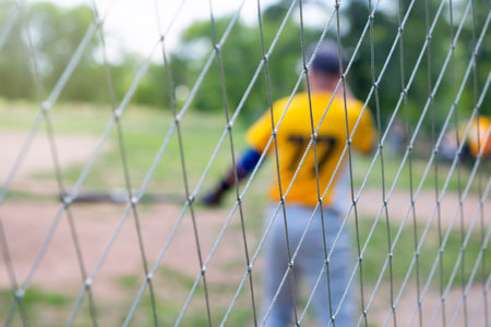 Baseball player in blur on the field, over a wire mesh fence.の写真素材
