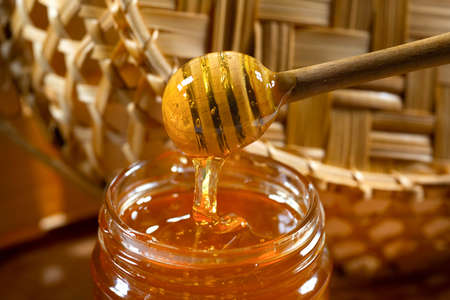 Honey drips from the honey bucket into the jar. Close-up. Healthy organic thick honey.の写真素材