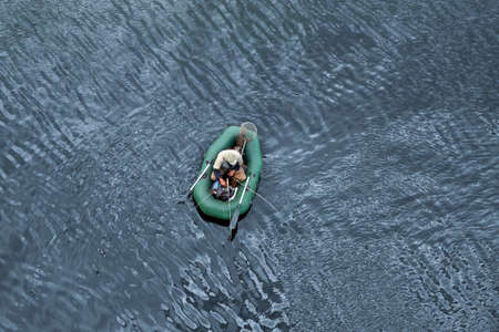 A fisherman in a rubber boat catches fish on the river. Top view, close up. Life style.