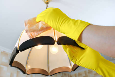 The cleaner wipes the dust from the chandelier. House cleaning.