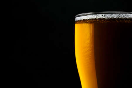 Glass of fresh beer isolated on a black background. Close-up.