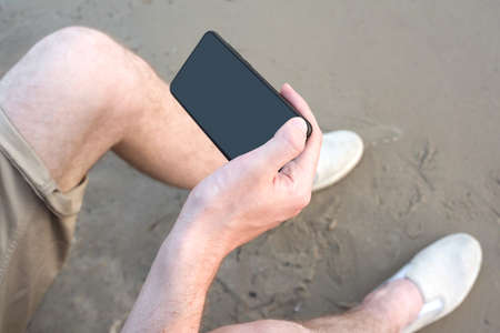 Mobile phone in the hands of a blogger by the river. Side view, life-style.