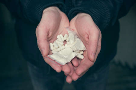 Drugs in the hands of an addict, close up. Addiction concept.の写真素材