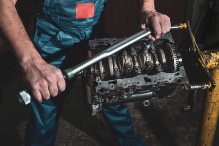 A mechanic with a wrench is repairing a car engine. Car maintenance concept.