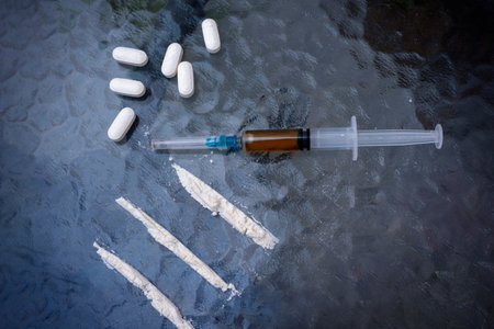 Syringe, cocaine and pills, on a glass table. Top view. Addiction conceptual image.の写真素材