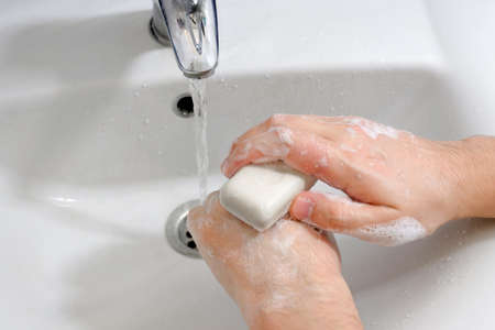 Hands under the tap with water over the sink in the bathroom. Hygiene concept.