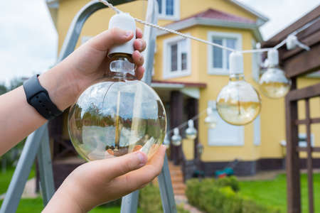 Incandescent lamp in hands close-up. Backyard cleaning.の写真素材