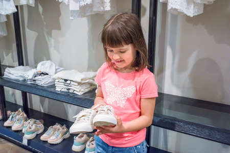 A little girl is shopping at the mall. The child chooses shoes.の写真素材