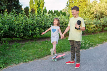 Children play outdoors and listen to music. Background summer park, golden hour.の写真素材