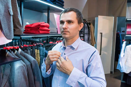 A man in a clothing store measures his shirt. Shopping at the mall.