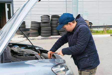 Trainee auto mechanic works in a garage, outdoors. Automobile Repair Service Concept.の写真素材