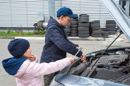 Children are repairing the car outdoors. Auto repair concept.の写真素材
