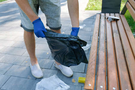 Male hands collect plastic waste in a public park. Territory cleaning. Environmental problems....