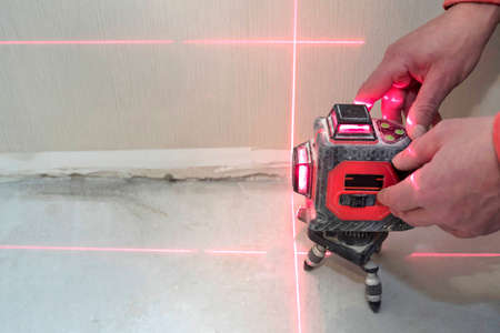 Construction laser level and the hands of a worker. The builder measures the level. Repair concept.の写真素材