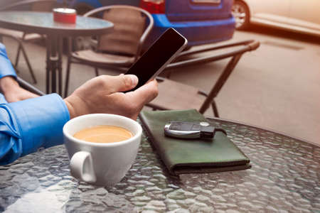 Cup of coffee and hand of man with a cellular telephone for Your advertisement text message.の写真素材