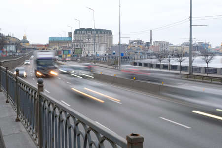 Cars in motion in the city. Cars move along the city road at dusk.