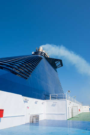 Ferry in the sea and smoke from the chimney against the blue sky. Transport and travel concept.