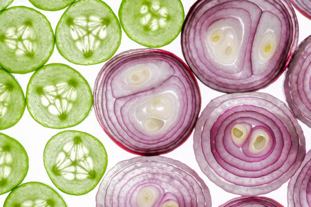 Cucumber and red onion slices isolated on white. Organic vegetables slices top view.の写真素材