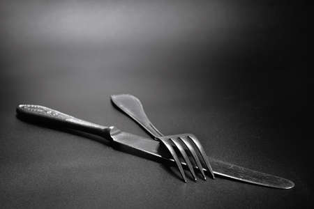 Stainless steel knife and fork on a black background. Cutlery close-up.の写真素材