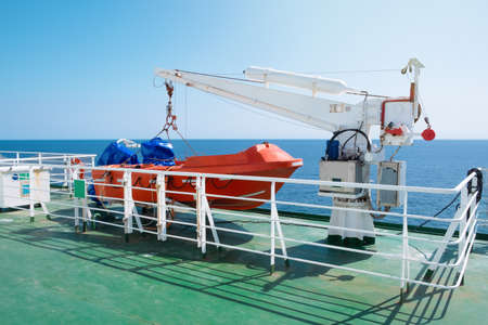 Lifeboat and crane aboard a ferry or cruise ship at sea. Transport and travel concept.の写真素材
