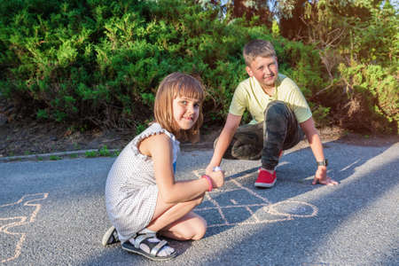 Children outdoors paint on the pavement and pose for the camera.の写真素材