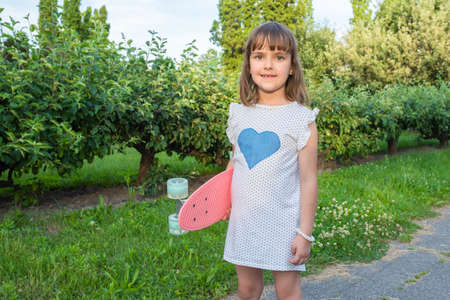 Girl with a skateboard in hands outdoors.の写真素材