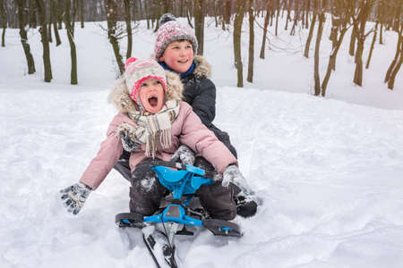 Children in winter outdoors ride a snow scooter.の写真素材