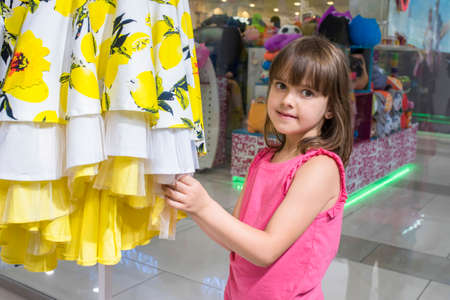 A happy child in a store chooses a dress. The concept of shopping.の写真素材