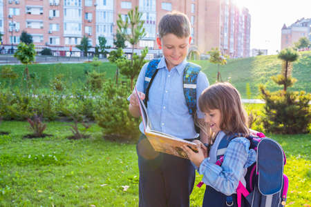 Elementary school students with a textbook outdoors. Back to school.の写真素材