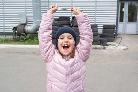 Portrait of a happy little girl with a wrench on the background of the garage. Repair service.の写真素材