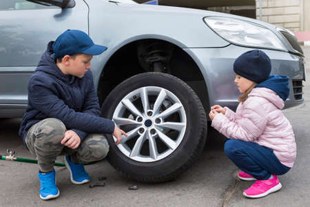 Boy and girl at a car service. Wheel replacement on a car, repair services.の写真素材