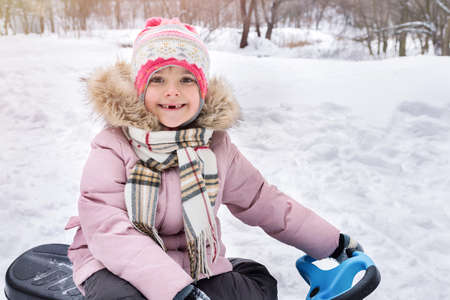 Portrait of a little girl in winter clothes in the park. Happy childhood and active winter holiday concept.の写真素材