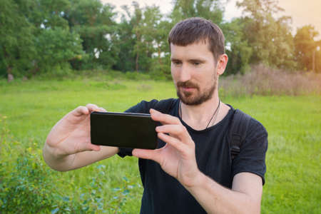 Tourism concept. A male traveler in the woods is filming a video on his phone. Active leisure,...