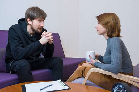 A man at a consultation with a psychotherapist, discussing his problems in the office. Social problems, depression, crisis.の写真素材