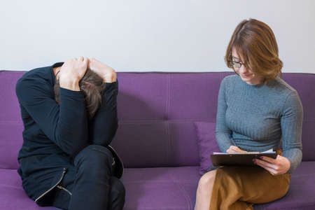 Unhappy person with a psychologist in the office, shares with his problems. Healthcare concept, depression. Emotional health problems.の写真素材