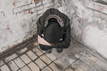 A teenager sits alone after using drugs and alcohol in an abandoned house. Addiction concept.の写真素材