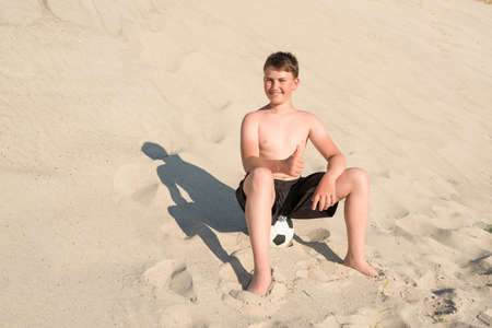 Happy teenager with soccer ball on the beach. Vacation sports games, sports, vacation, lifestyle.の写真素材
