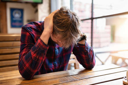 Sad lonely man sits at the bar at the table. Depression, crisis, alcohol addiction, lifestyle. Alcoholism concept.の写真素材