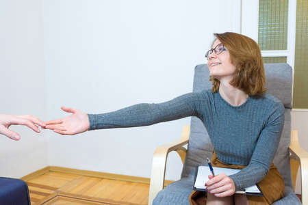 Mental health concept. Female psychologist holds out his hand to a patient experiencing depression. Consultation with a doctor.の写真素材